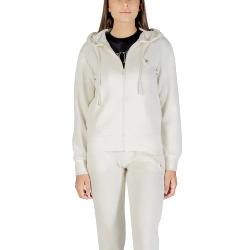 Frauen tragen beigefarbene Trainingsanzüge mit Kapuze und durchgehendem Reißverschluss mit schwarzem T-shirt, Guess Active Damen-Sweatshirt