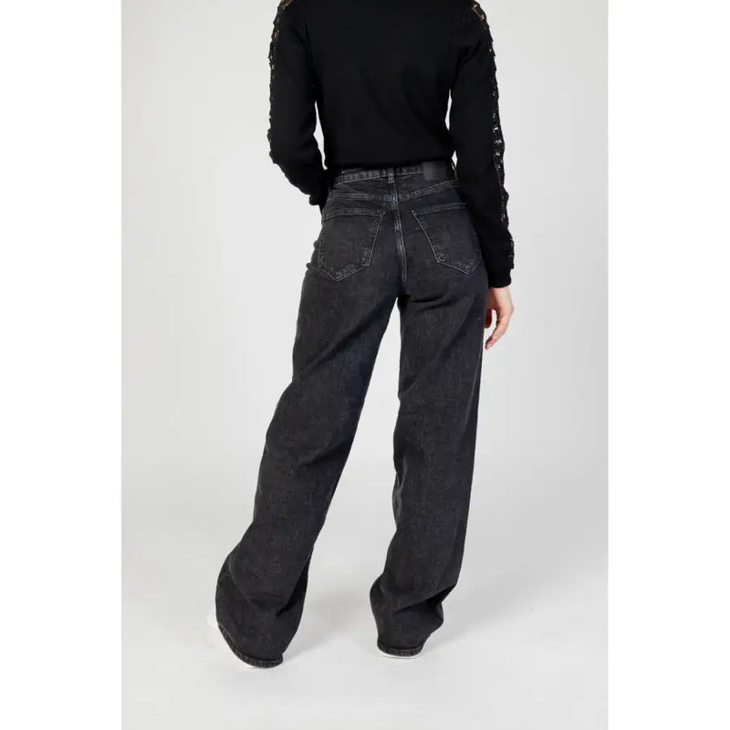 Schwarze Damen-Jeans mit weitem Bein, von hinten gesehen, mit verwaschenem Look und klassischen Gesäßtaschen.
