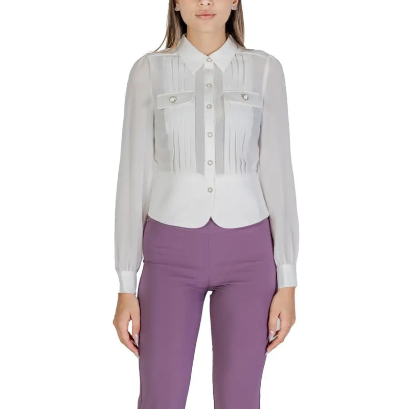 Women wearing white long-sleeved button-up blouse with pleats and purple trousers